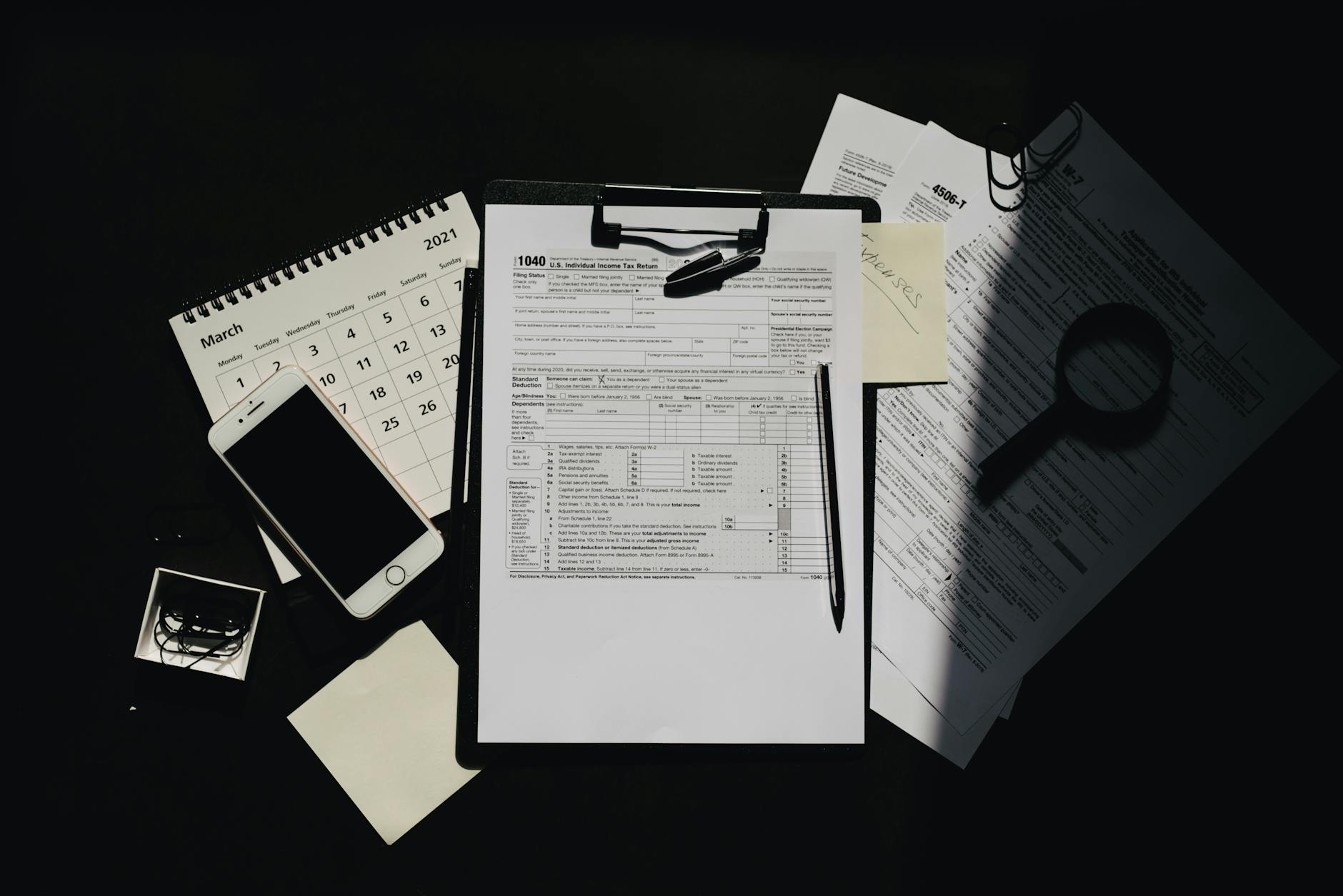 Dokumenty podatkowe, kalendarz i smartfon na ciemnym biurku