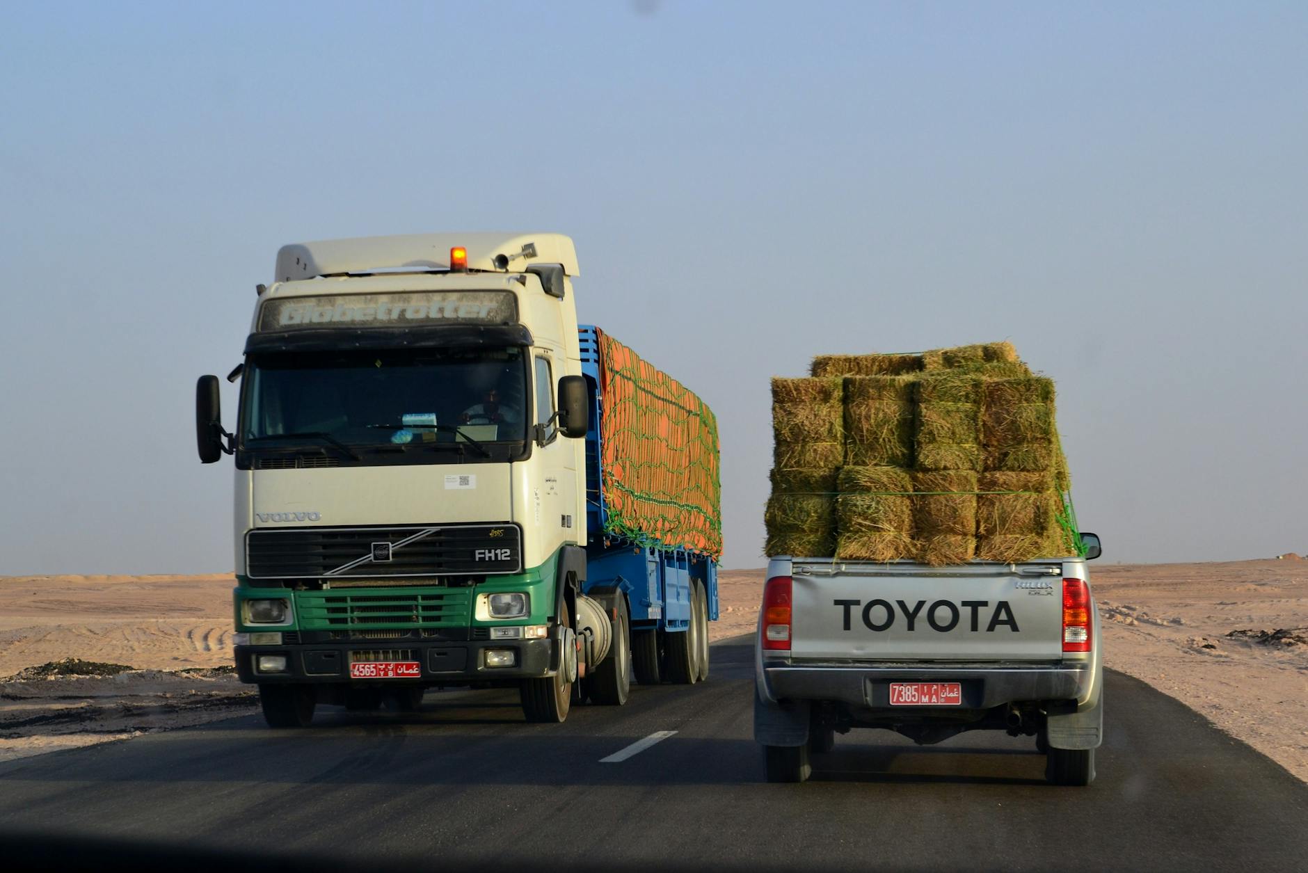 Ciężarówki z belami siana jadące autostradą przez pustynię w Omanie