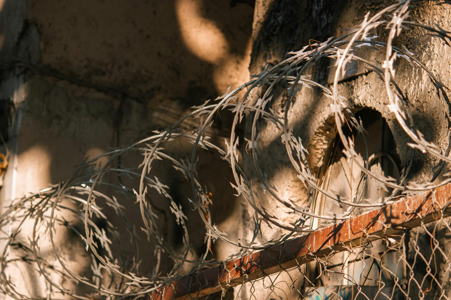 Drut kolczasty rzucający cienie na starą ścianę