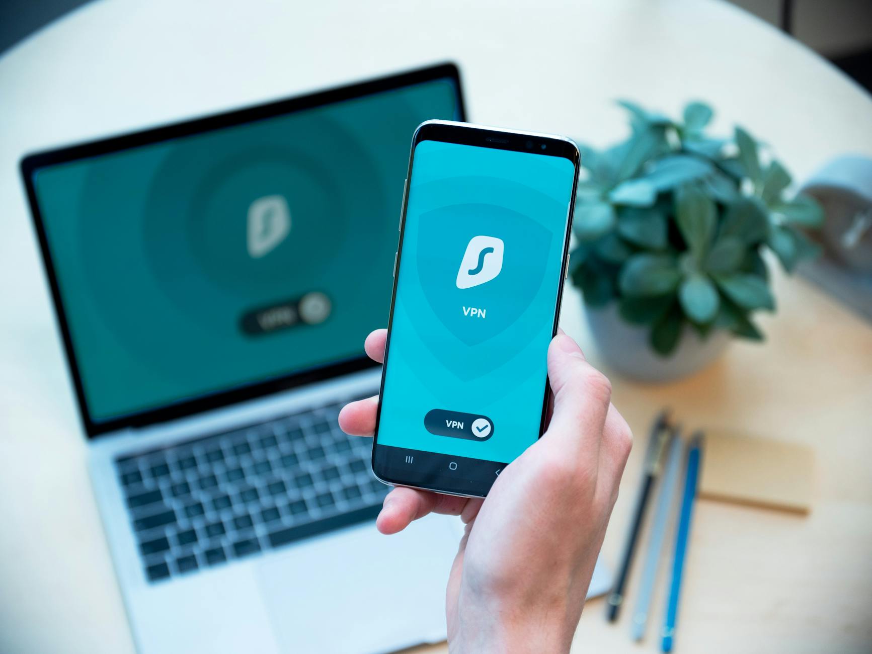 Smartfon z aplikacją bezpieczeństwa w dłoni na tle laptopa