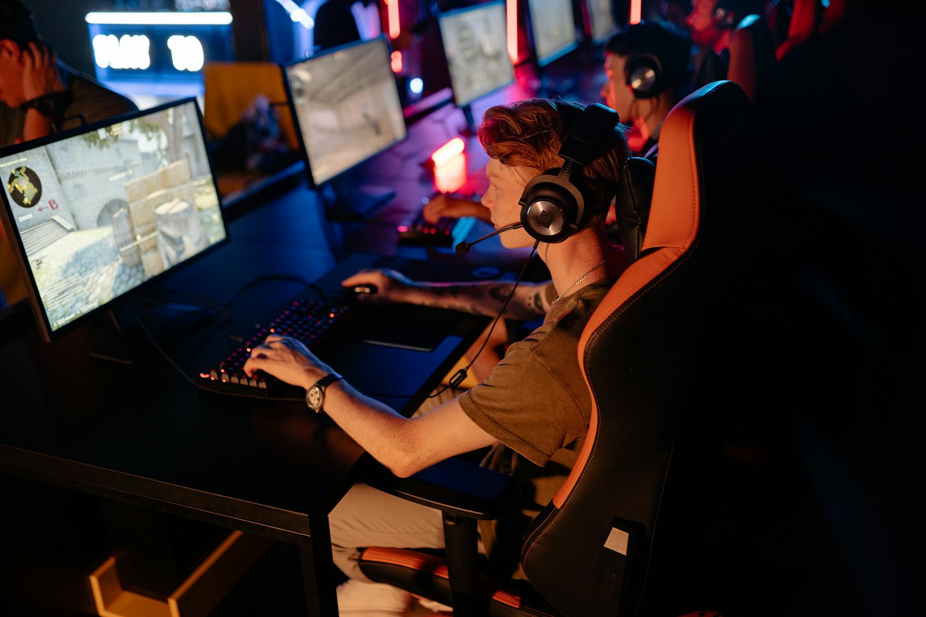 Gracze e-sportowi przy monitorach podczas turnieju w ciemnej arenie