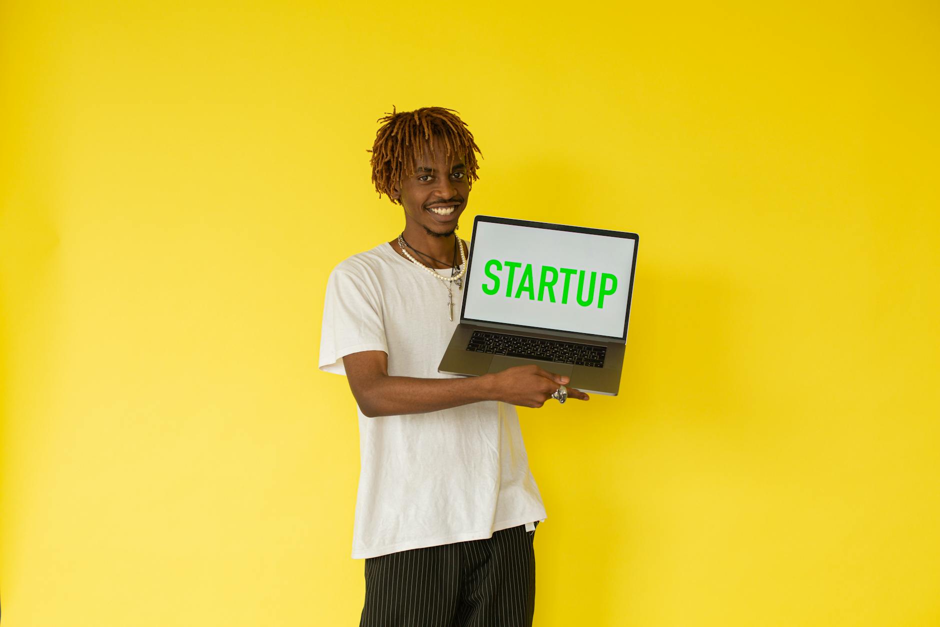 Uśmiechnięty mężczyzna z laptopem startupu na żółtym tle