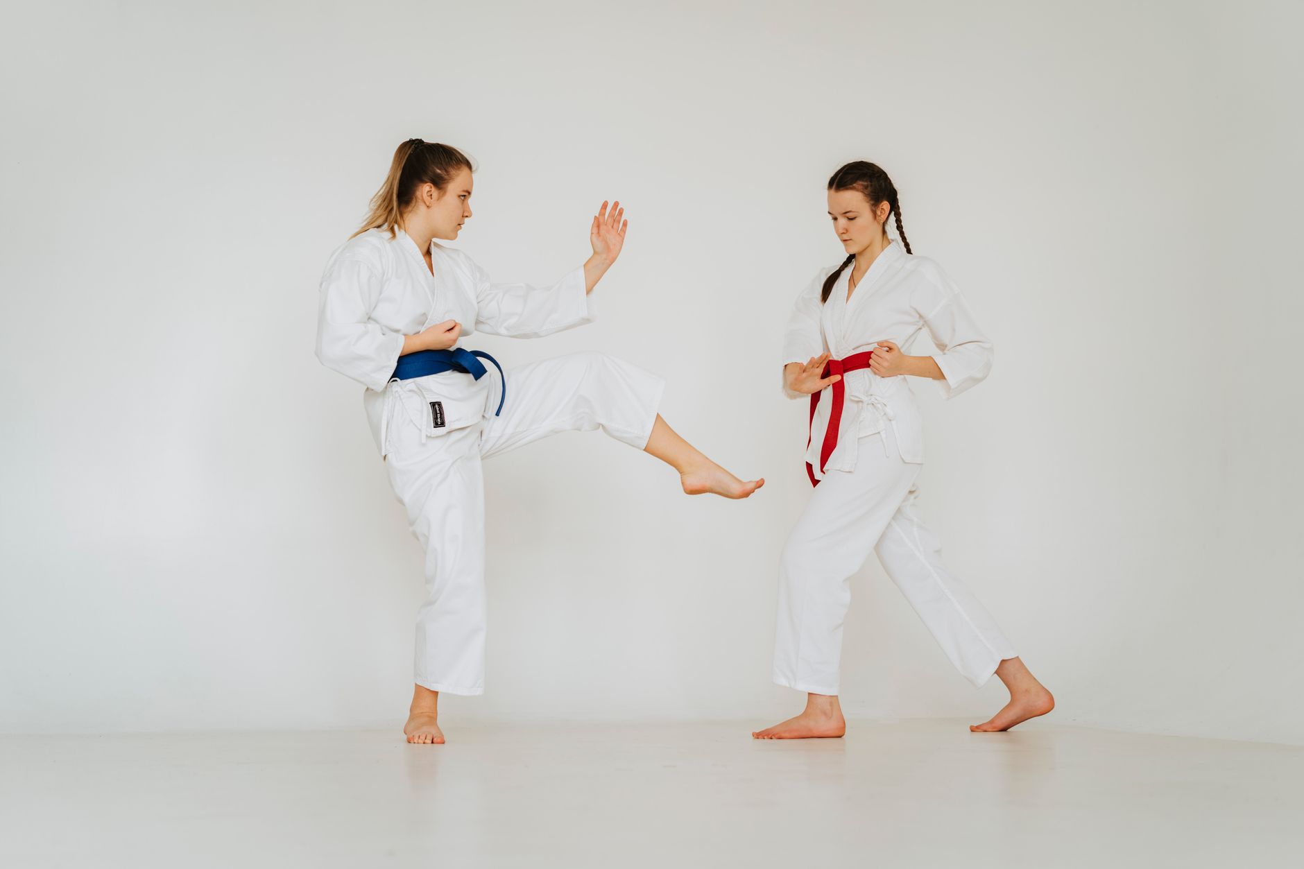 Dwie młode dziewczyny w kimonach trenują karate w jasnym dojo Dwie młode dziewczyny w kimonach trenują karate w jasnym dojo