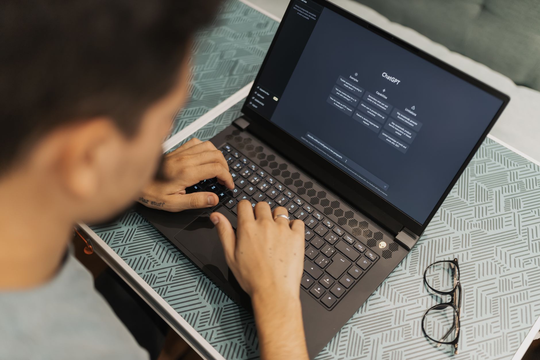 Mężczyzna w okularach pracuje na laptopie z otwartym programem AI
