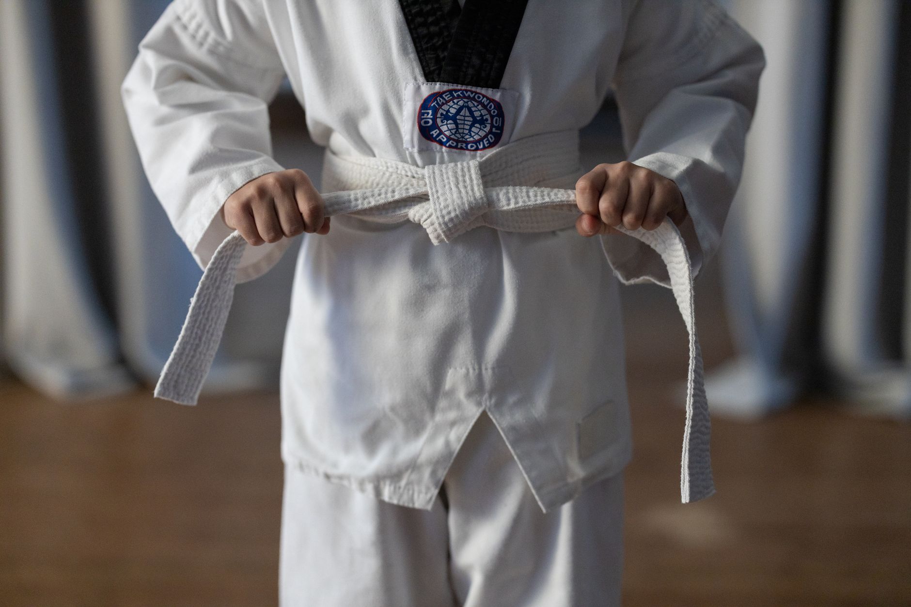 Początkujący karateka wiążący biały pas w tradycyjnym kimonie