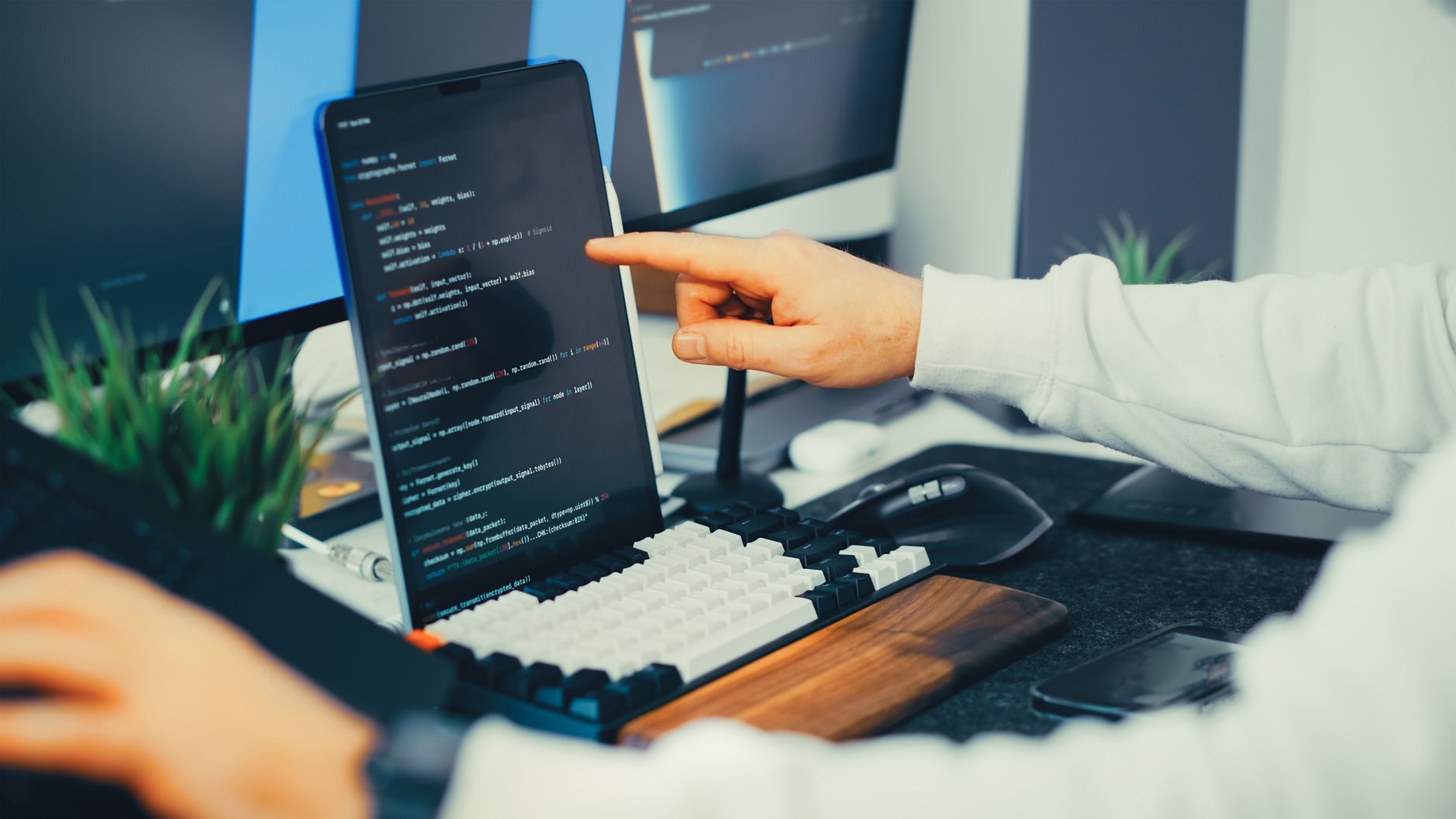 Programista przy biurku testuje aplikację na laptopie i monitorze