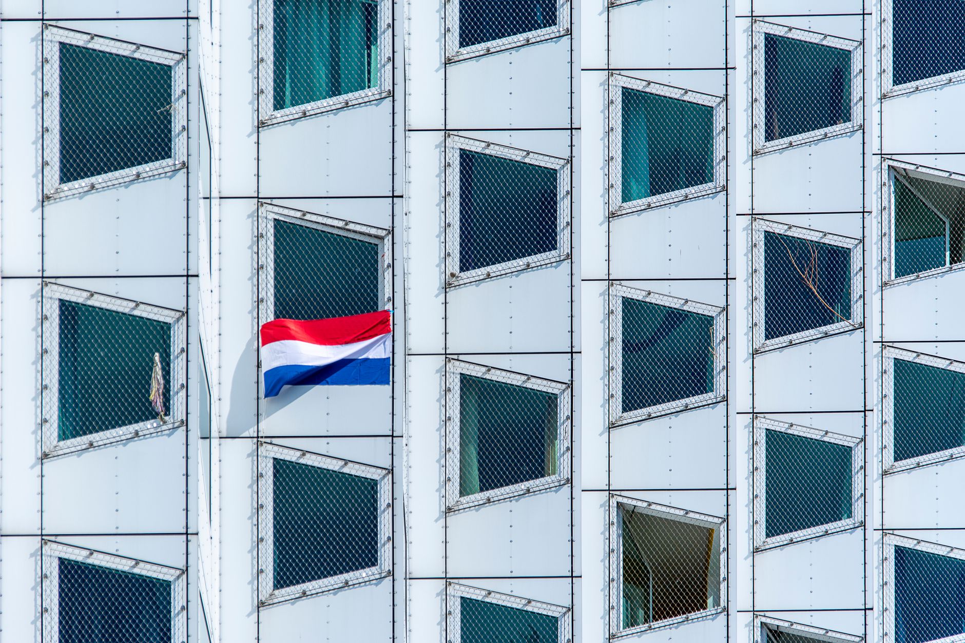 Abstrakcyjna fasada budynku z flagą Holandii i geometrycznymi oknami