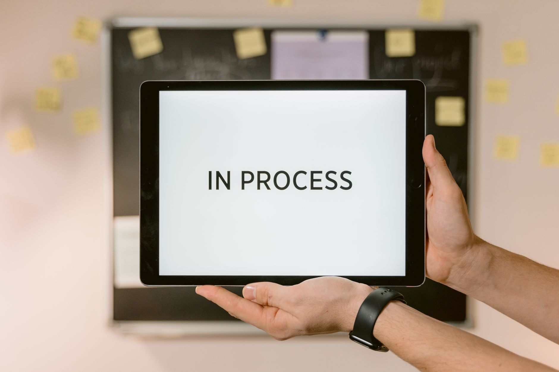 Dłonie trzymające tablet z napisem In Process symbolizującym przetwarzanie danyc