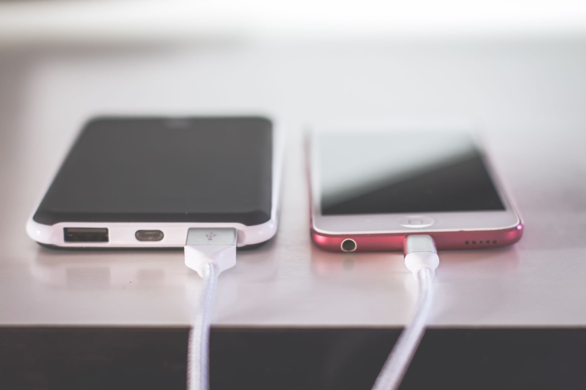 Dwa smartfony ładujące się obok siebie na biurku