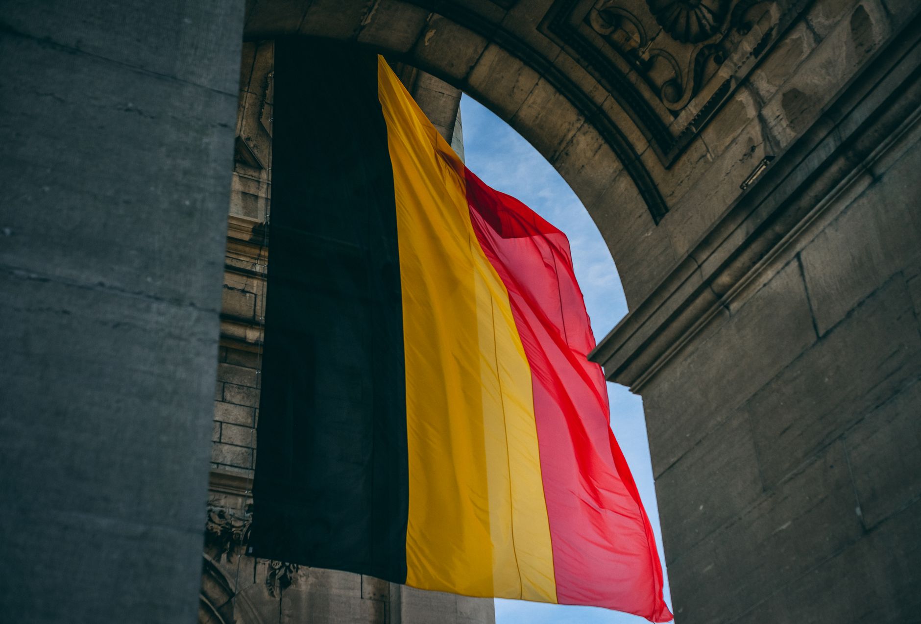 Flaga Belgii powiewająca pod łukiem w Brukseli
