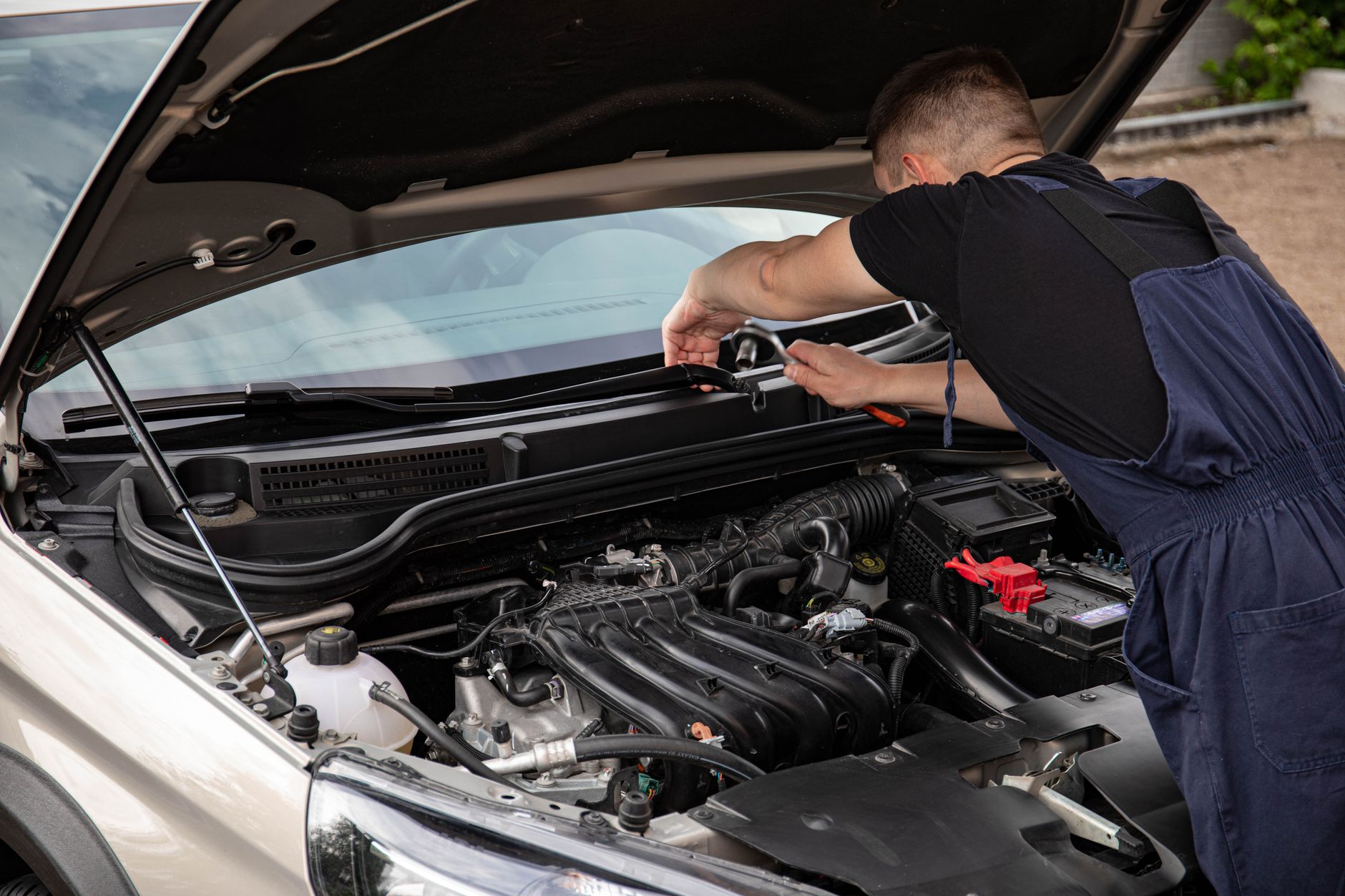 Mechanik naprawia silnik samochodu na zewnątrz w świetle dziennym