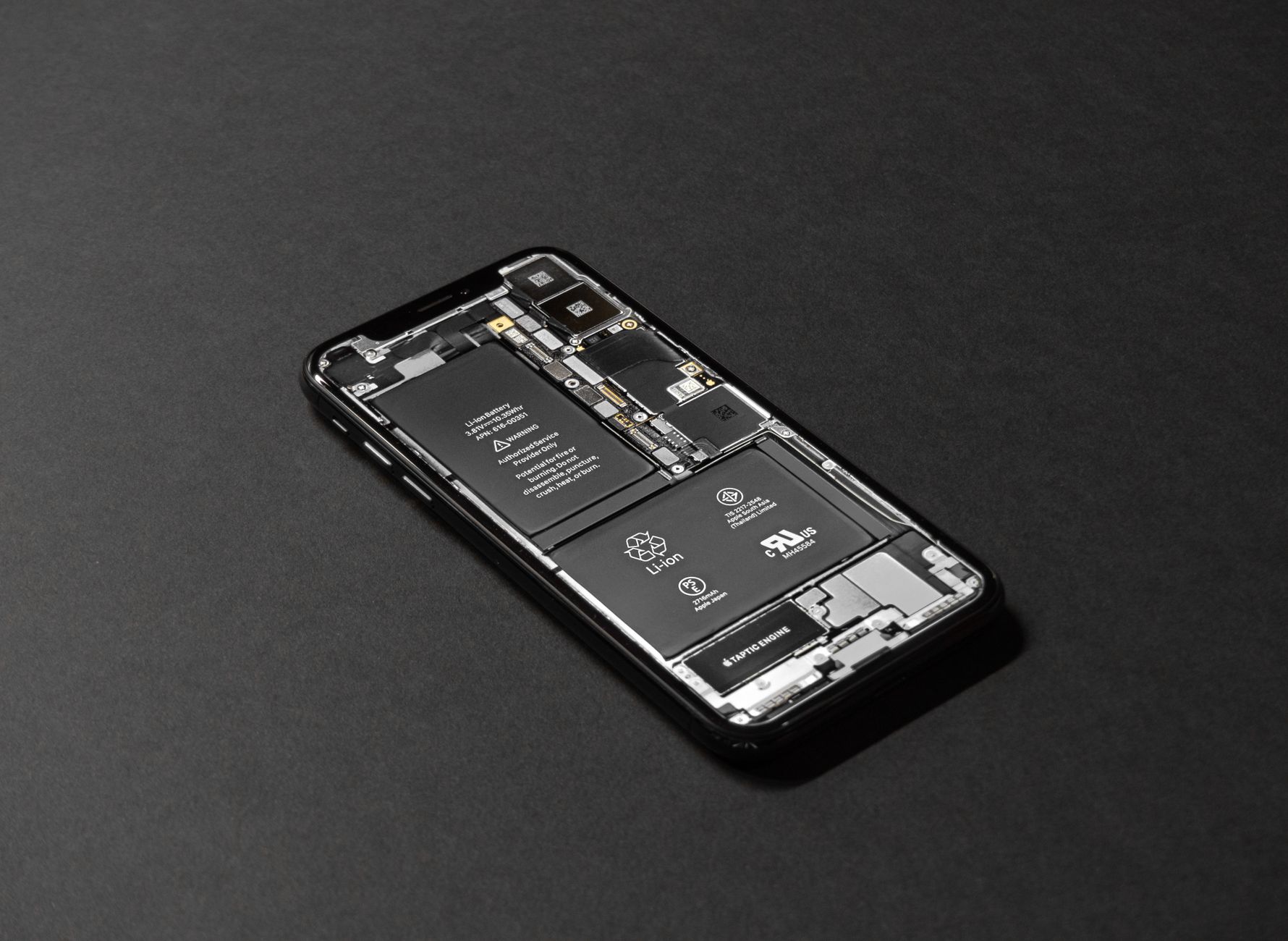 Smartfon z widocznymi podzespołami na ciemnym tle